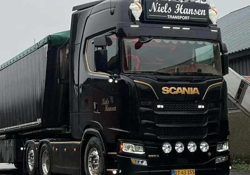 Sort lastbil med presenningtrailer på våd asfalt i gråvejr